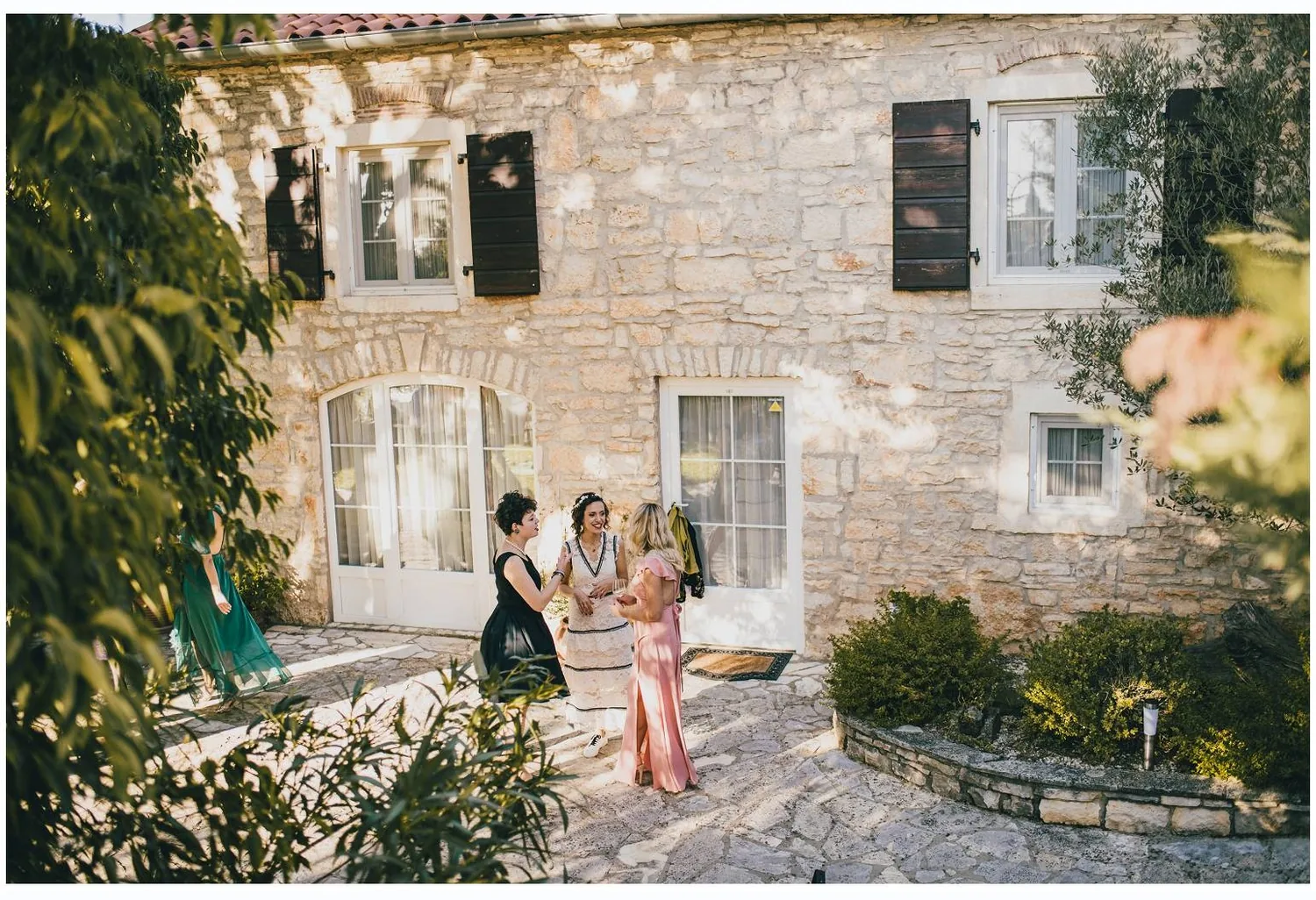 Gošće u razgovoru pred kamenom fasadom stancije u zalasku sunca